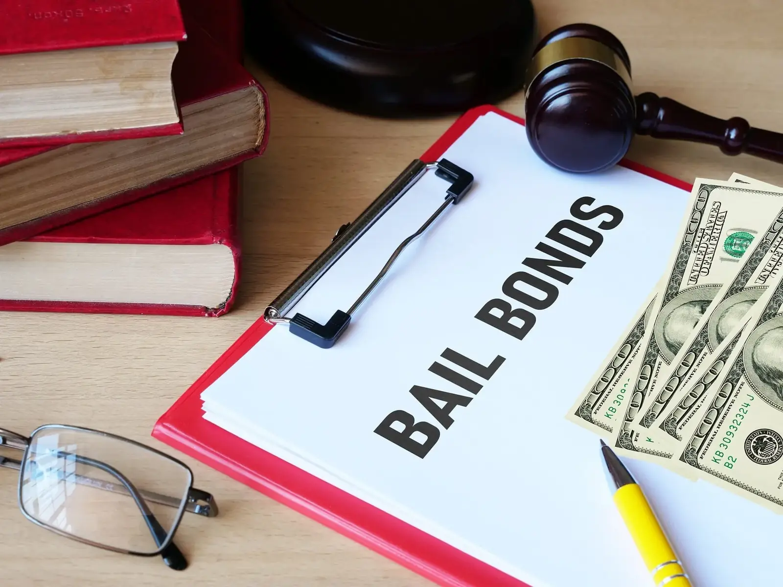 Bail bonds paperwork on a clipboard beside a gavel and law books
