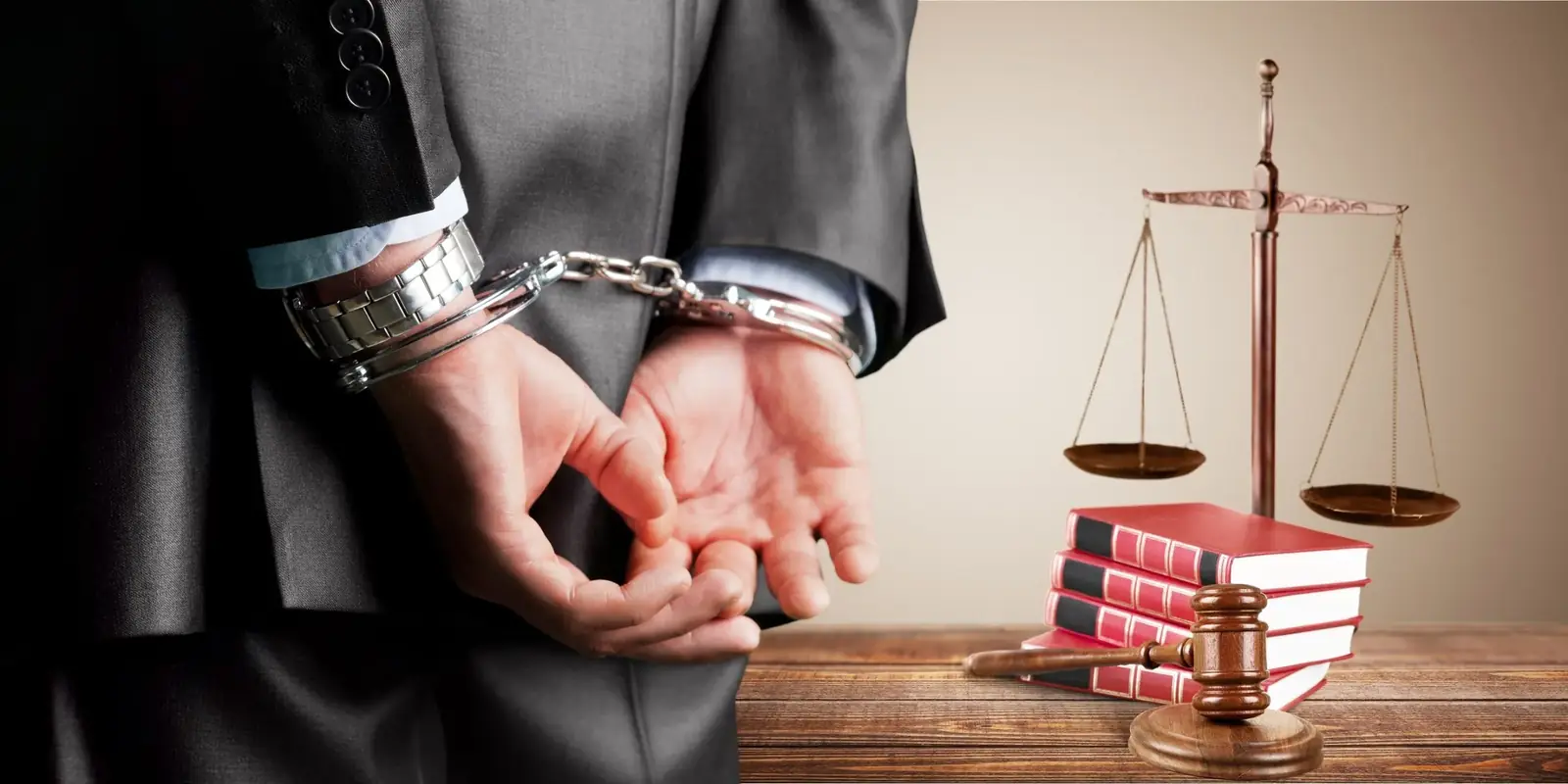 Handcuffed defendant standing beside the scales of justice