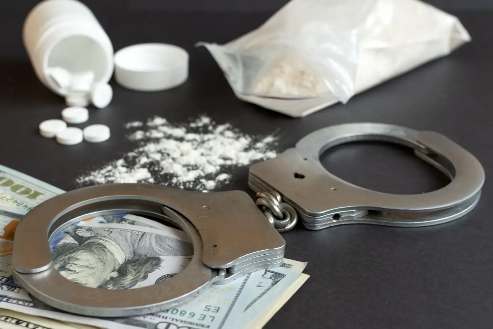 Pills, powder, cash and handcuffs laid out as drug case evidence
