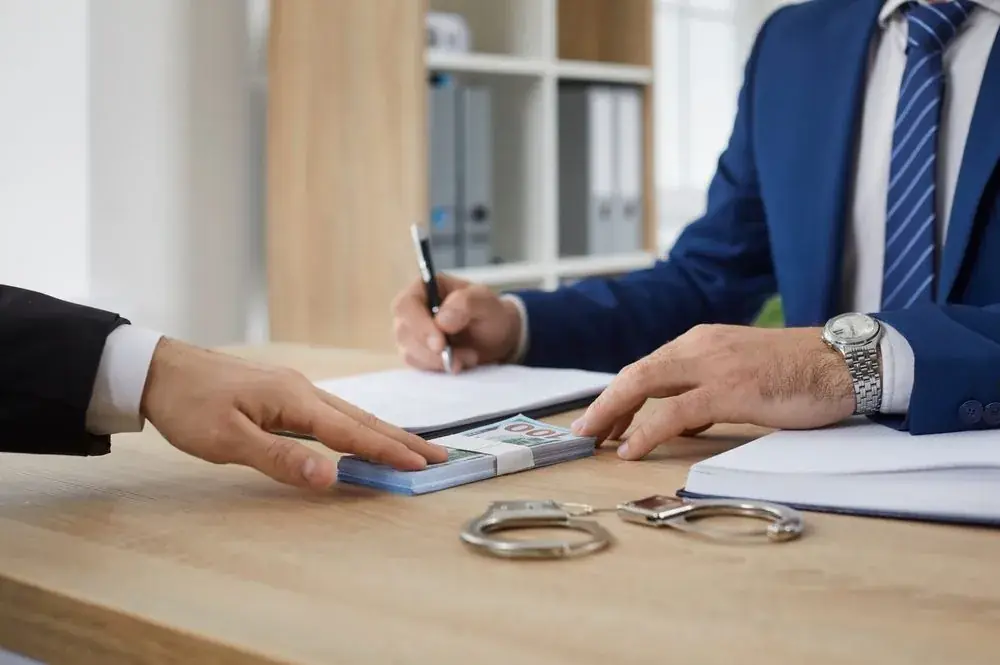 Indemnitor signing bond paperwork with handcuffs on the table
