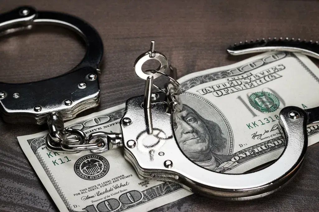 Handcuffs resting on hundred dollar bills